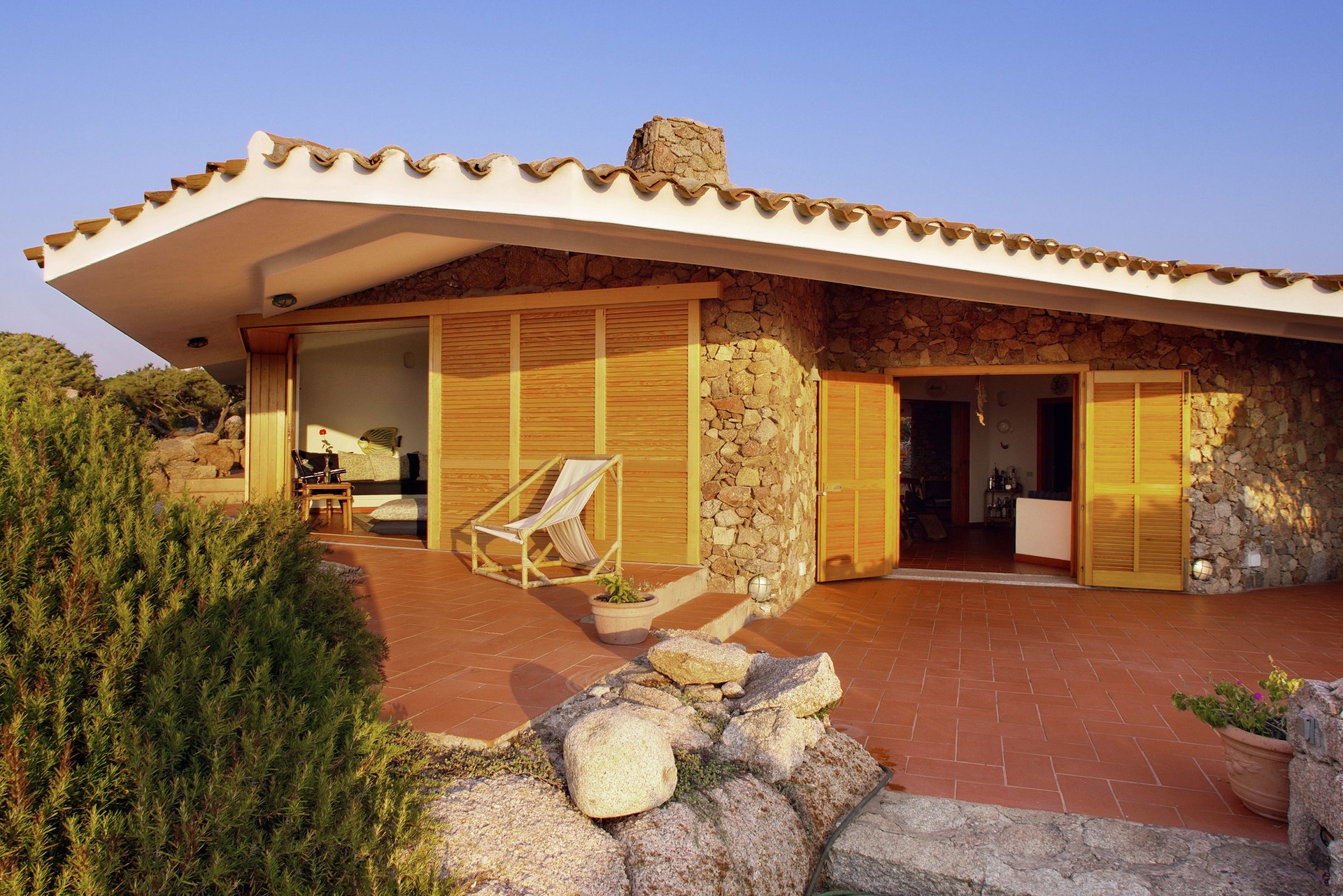 Seaside house in stone, brick and wood, rosemary plants, Sardinia